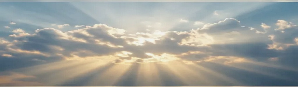 Soft golden heavenly light breaking through peaceful clouds in a wide panoramic sky